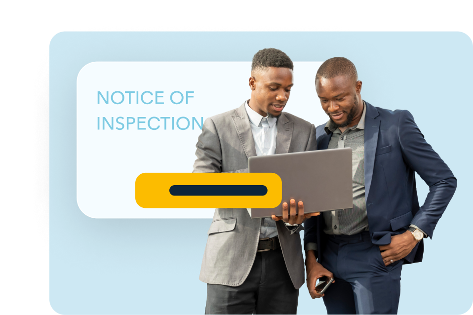 2 men standing looking at a laptop with the words notice on inspections behind them